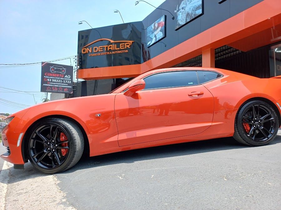 Camaro laranja na frente do estúdio